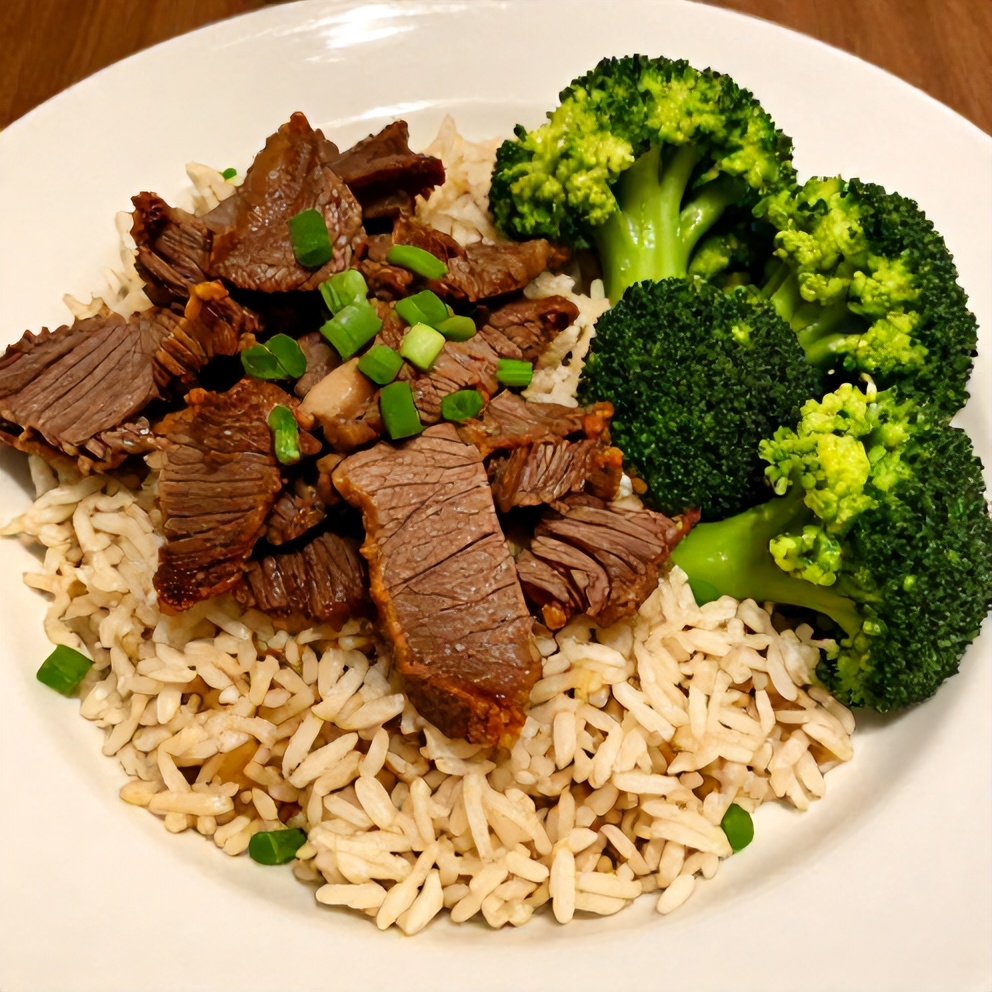 Plated serving of Beef and Broccoli Rice Bowls on a white plate, garnished with green onions, showing crispy beef and tender broccoli.