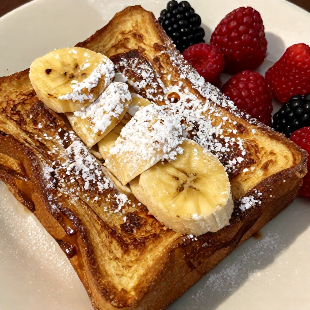 Plated serving of Overnight Banana French Toast Casserole with a dusting of powdered sugar